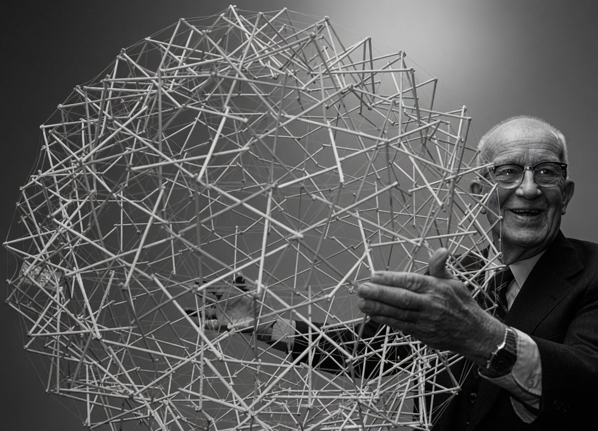 Buckminster Fuller standing among his geodesic tensegrity structures, black and white photograph.